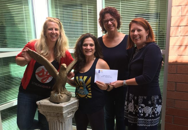 Strong Girls Serve Co-Founders receive checks from 100+ Women Who Care Athens member, Kim Klonowski, and founder, Sherry Clouser